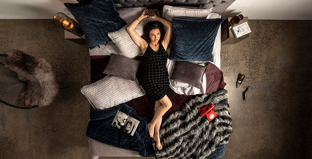 A woman lying back on pillows on a luxury SleepMaker mattress