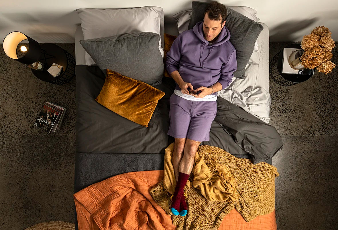 A man sitting on his bed, looking at his phone