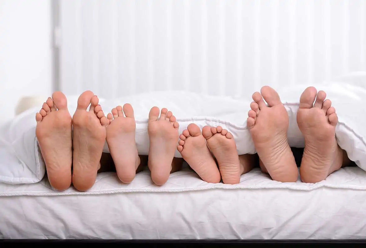 Feet lined up across a mattress