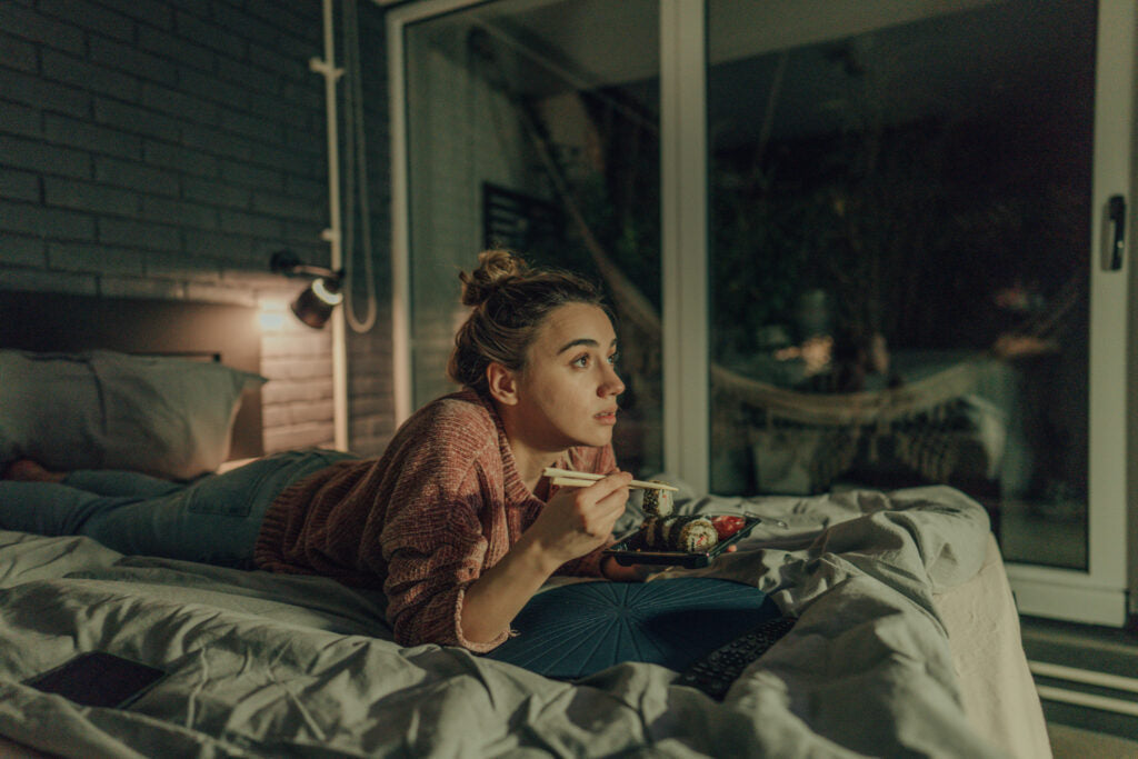 A young woman relaxing in bed watching TV