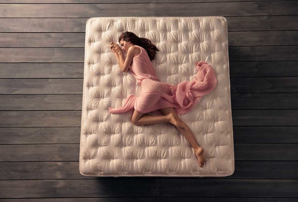 A woman in a pink dress lying across a SleepMaker Cocoon mattress