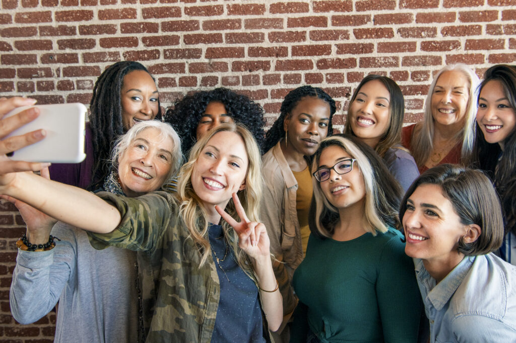 A group of women taking an ussie in front of a brick wall