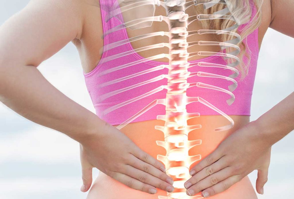 A stylised image of a glowing spine and ribs superimposed over a photo of a lady holding her lower back.