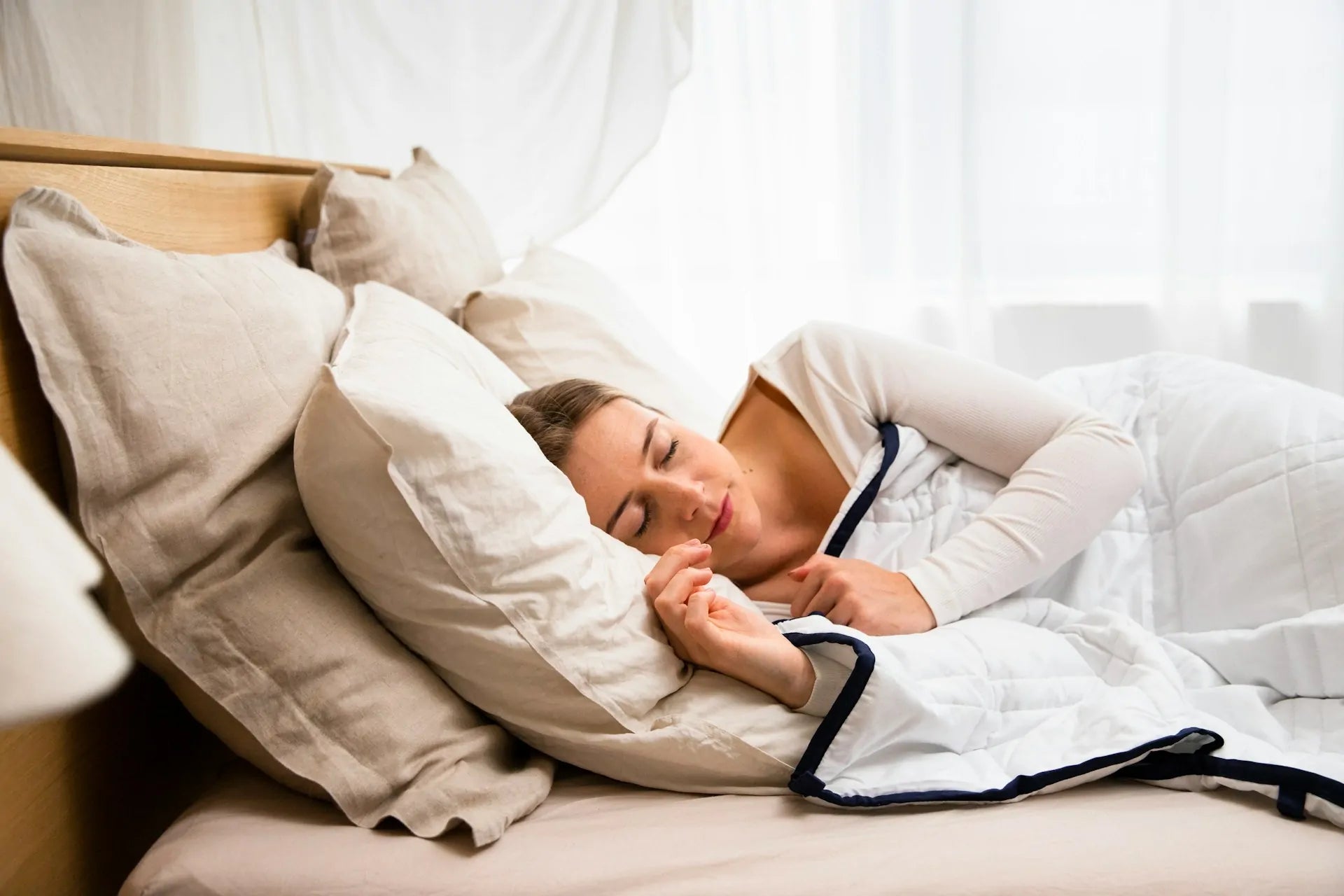 A woman lying on her side on a bed with pillows under her head