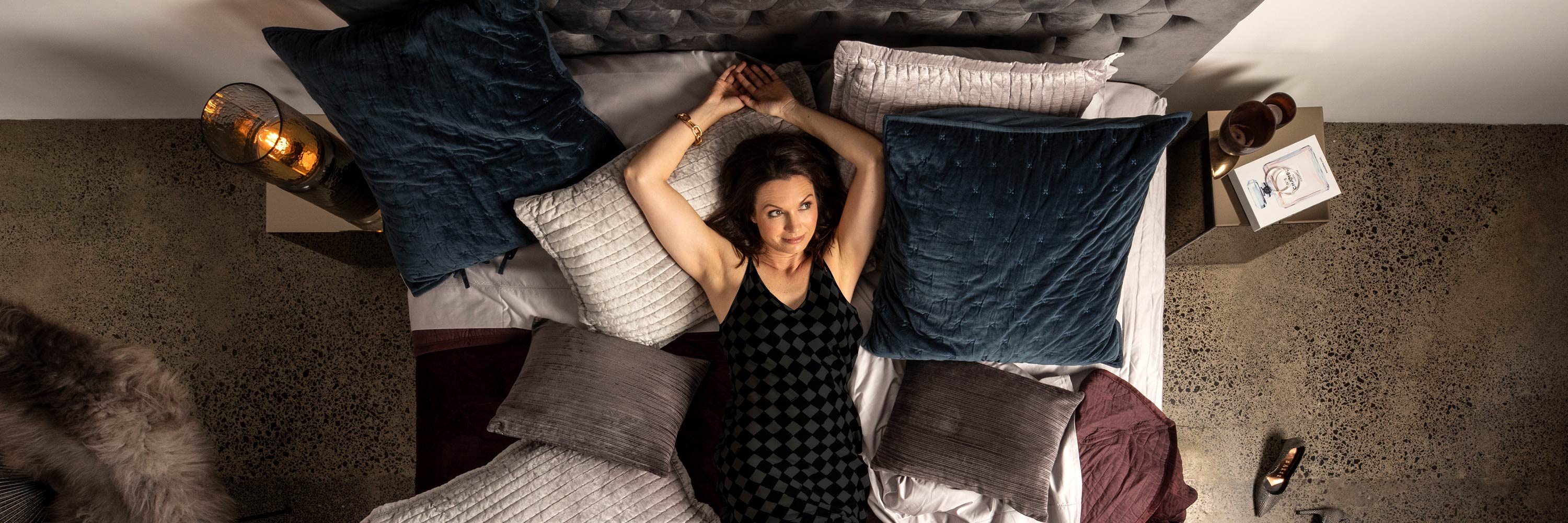 Woman lying on a SleepMaker bed in a room with various items around