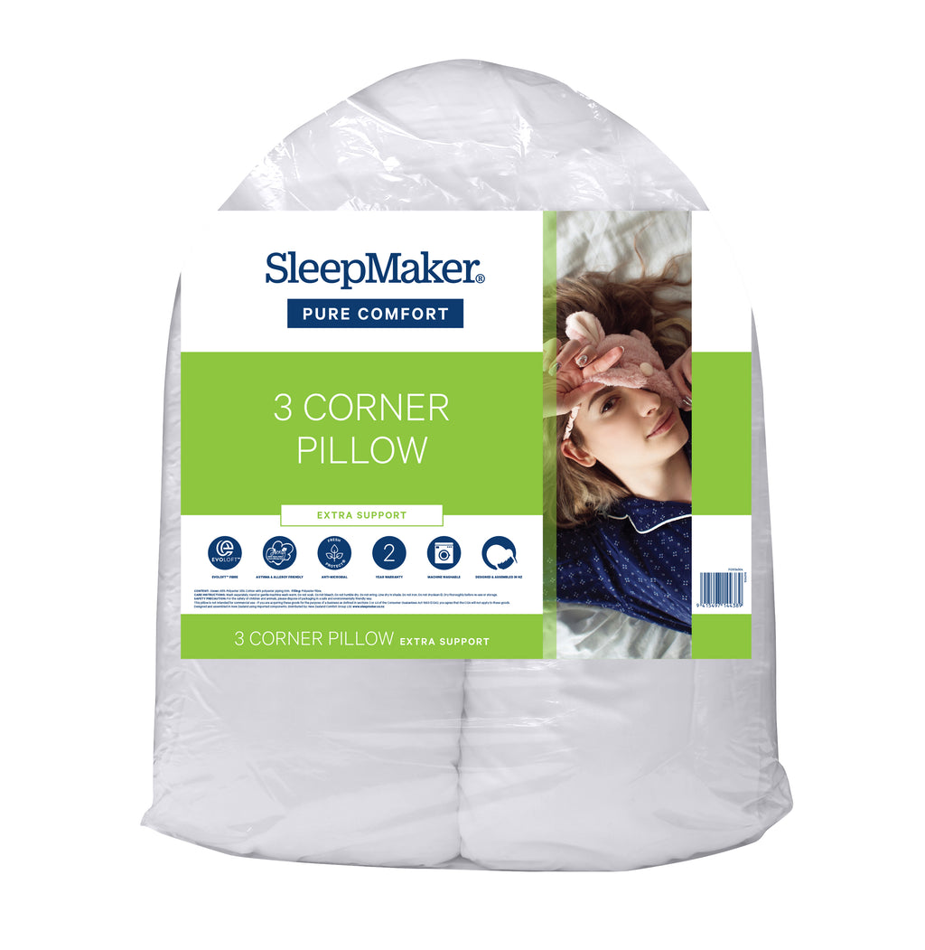 A packaged SleepMaker Pure Comfort 3 Corner Pillow, shown in its clear plastic wrapping with a green and white paper label featuring a photo of a woman resting.