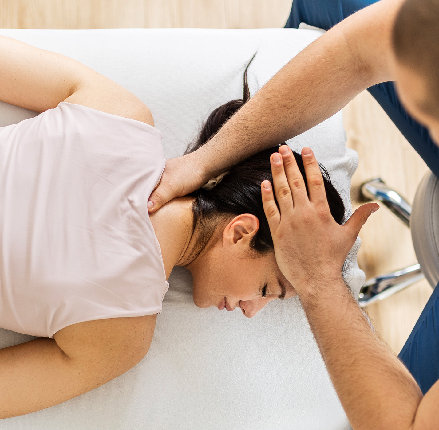 Person receiving a head adjustment from a chiropractor in a clinical setting.