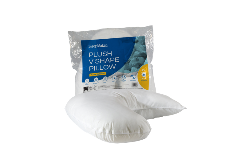 A SleepMaker plush V-shape pillow shown in its clear plastic packaging with a blue and yellow label, with the white pillow placed in front on a plain white background.